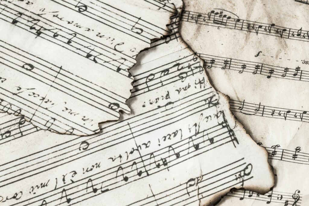 pexels-photo-934067-934067 Close-up of aged, burnt music sheets displaying musical notes and compositions in detail.